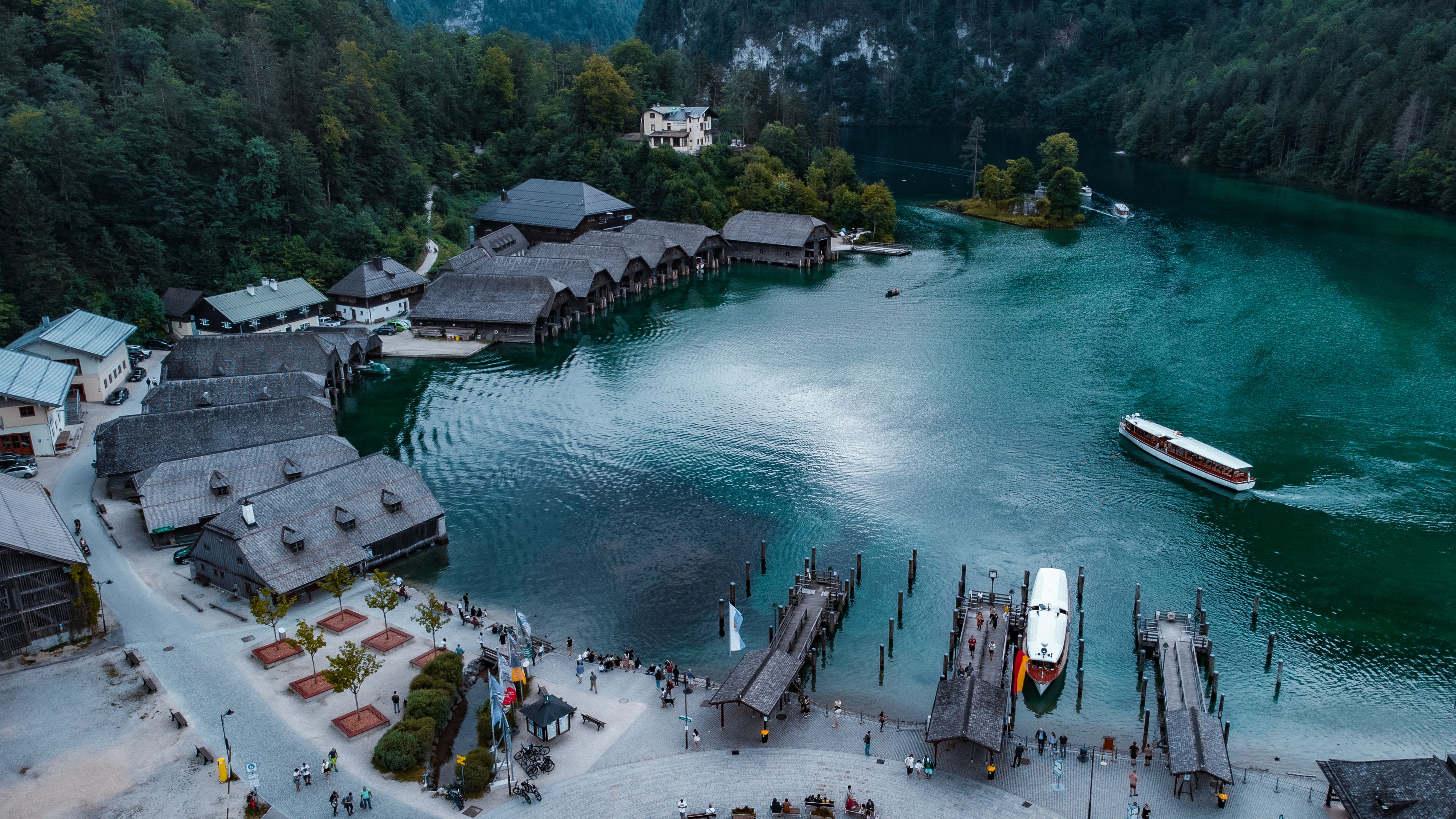 Aerial view of a tranquil Bavarian lakeside resort with boats, piers, and forested shores.