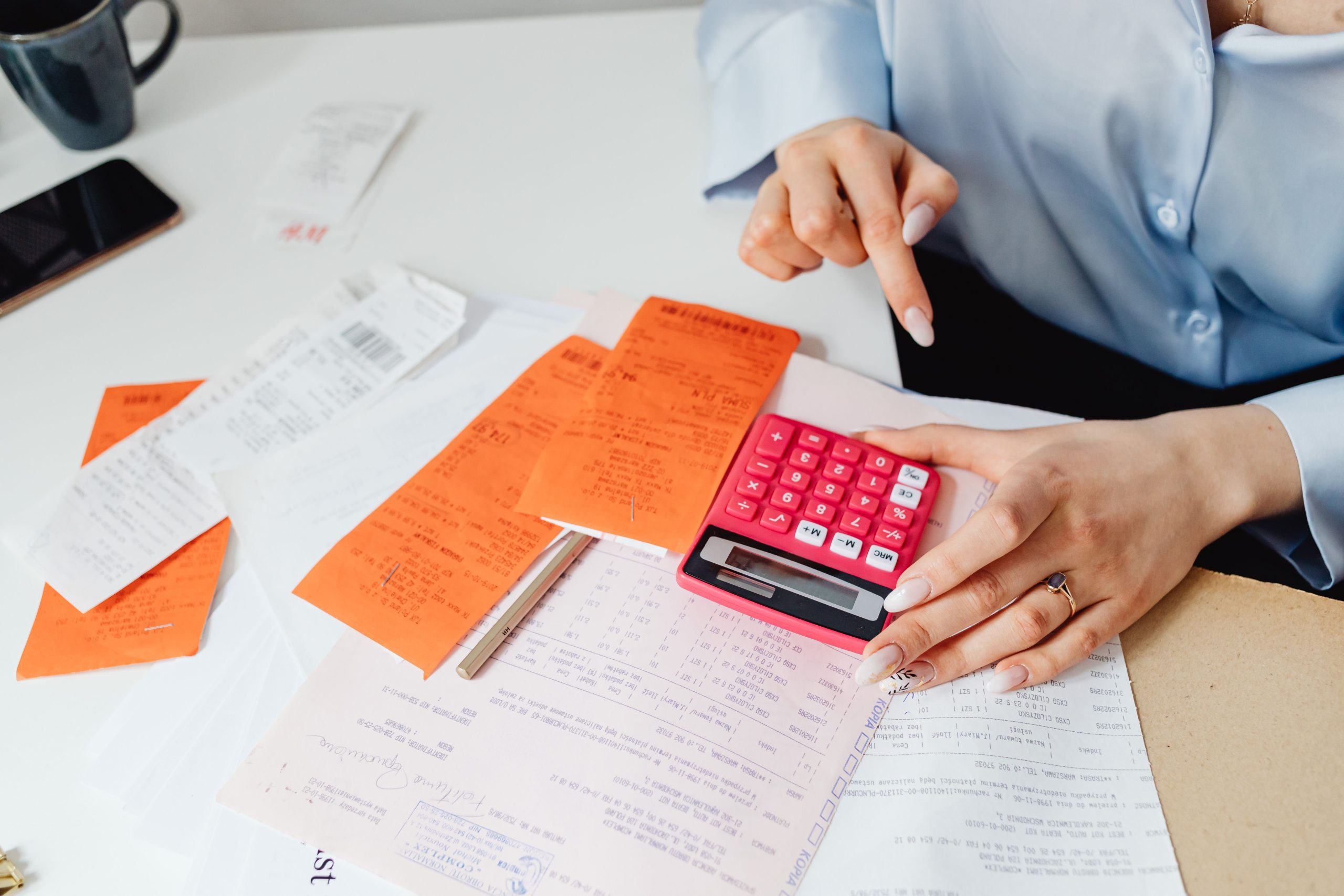 Businesswoman calculating expenses beside receipts and financial documents