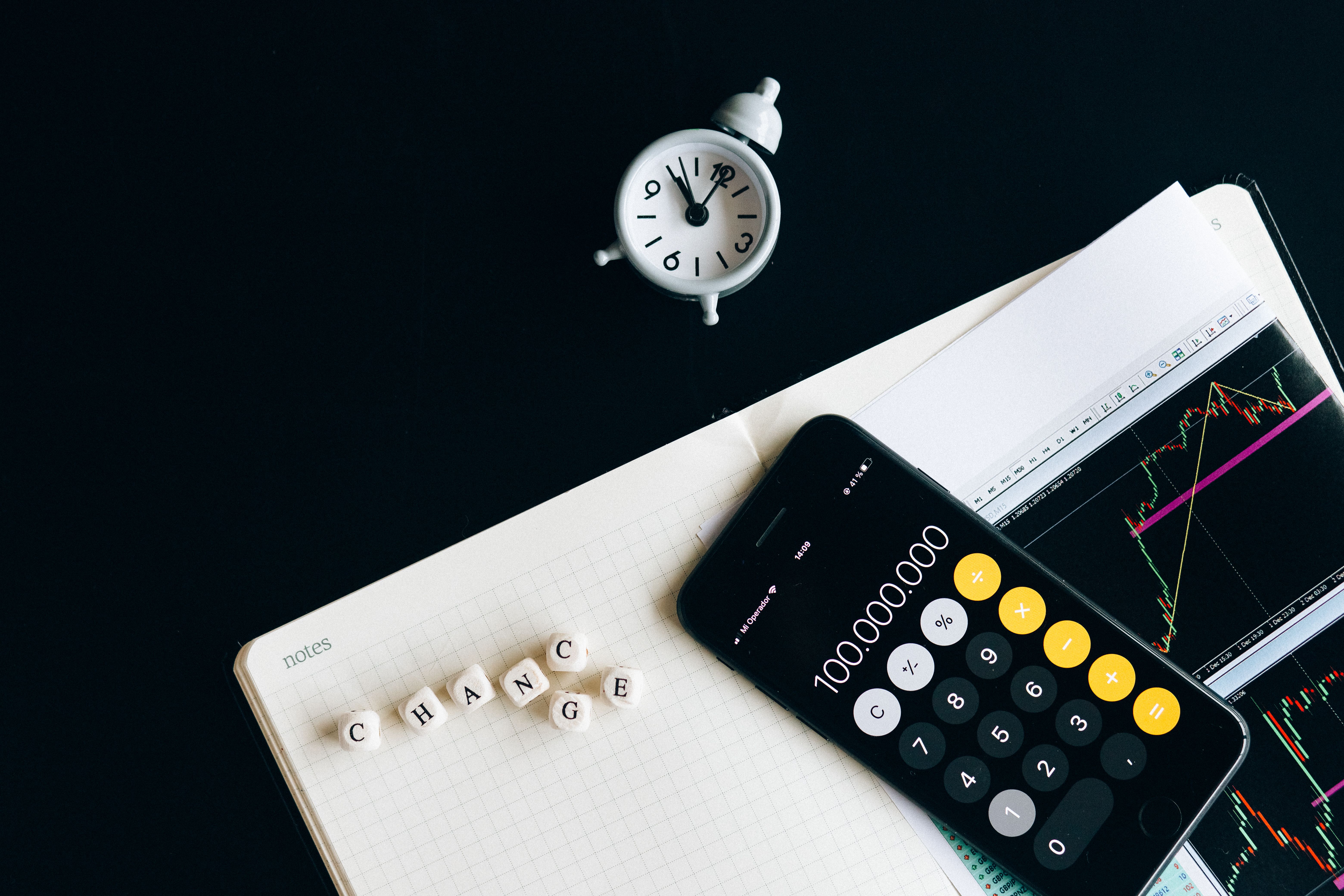 Notebook, smartphone, clock, and financial charts representing economic analysis and market planning