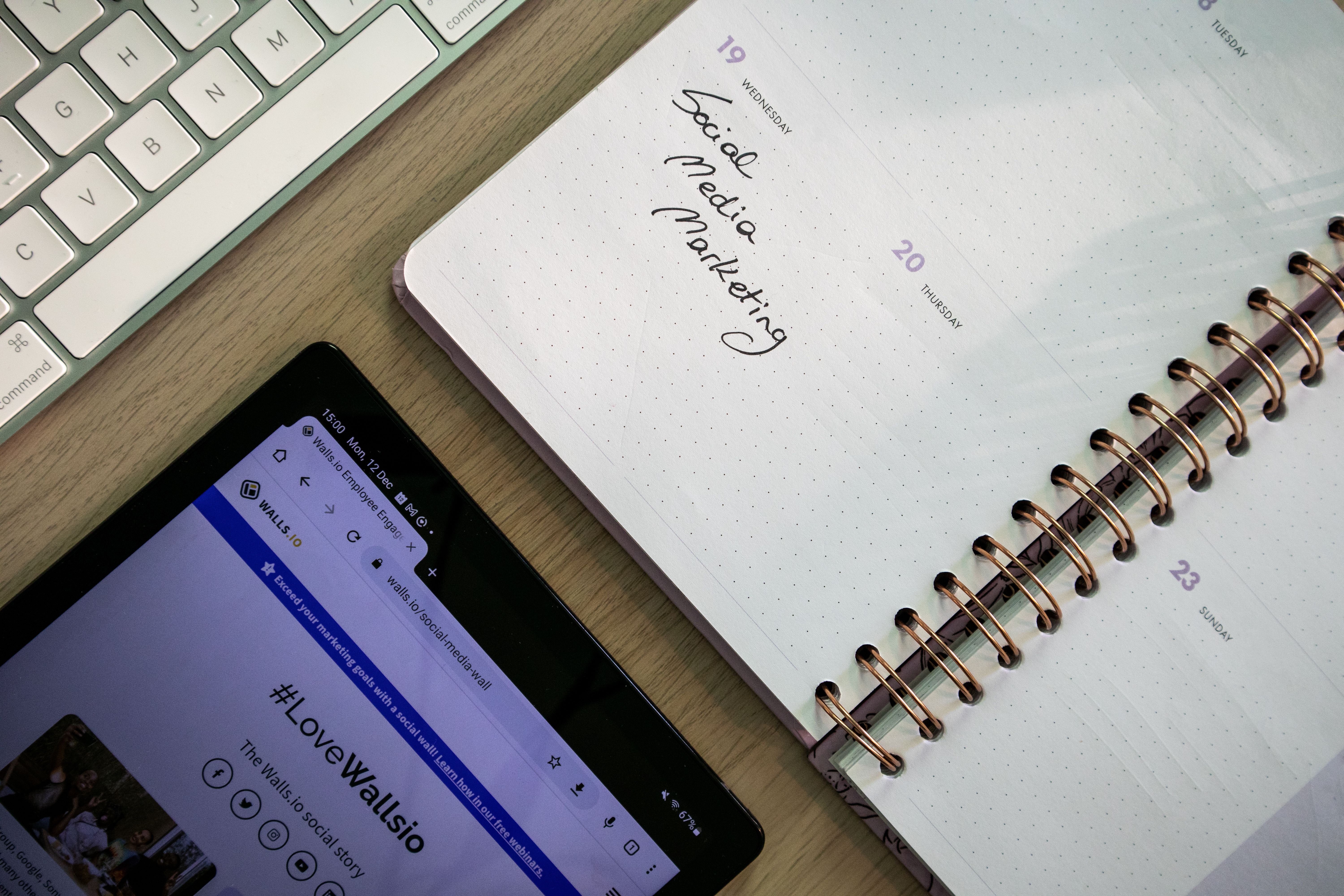 Tablet, notebook, and keyboard arranged for planning social media content