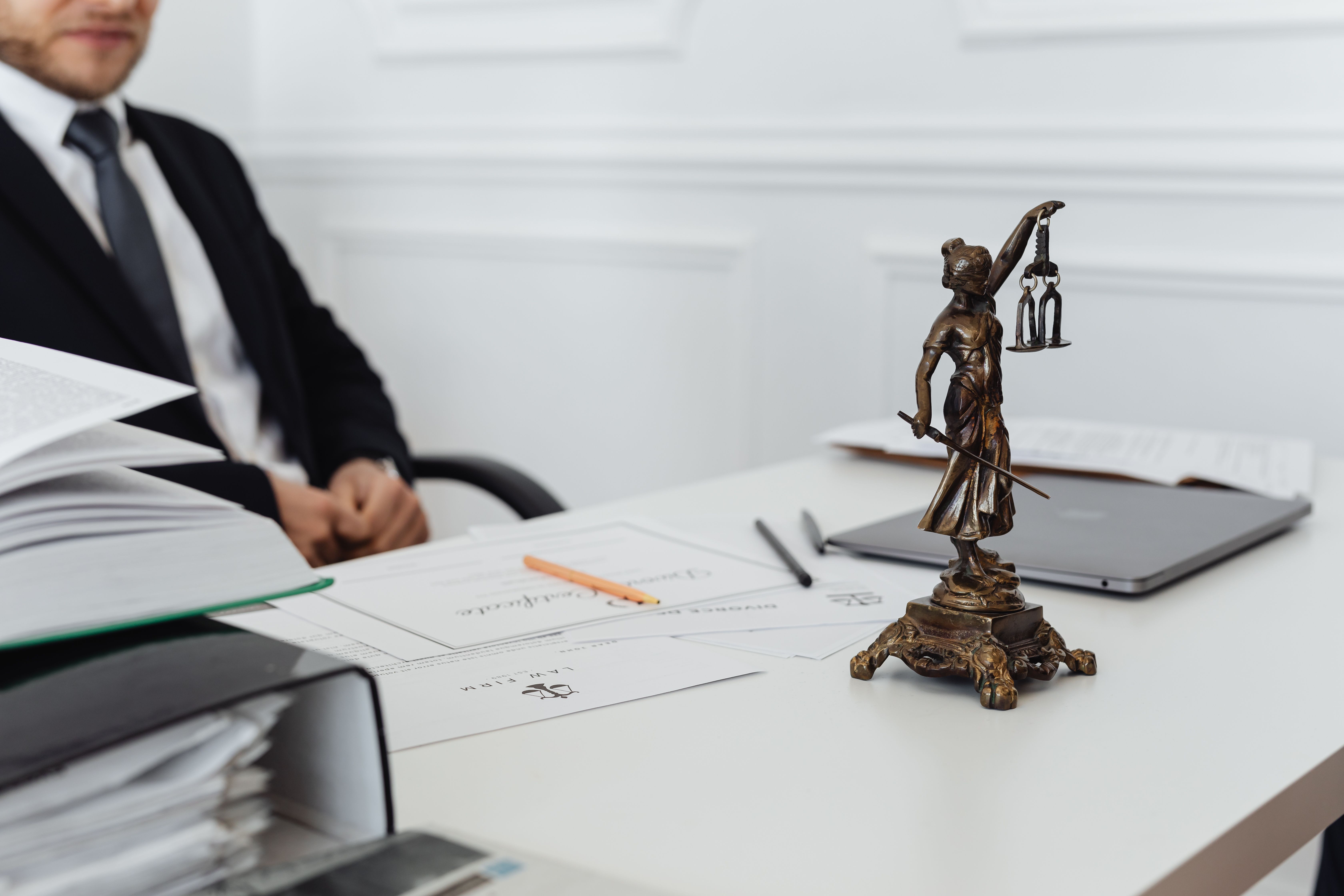 International law office workspace with Lady Justice statue, legal documents and laptop