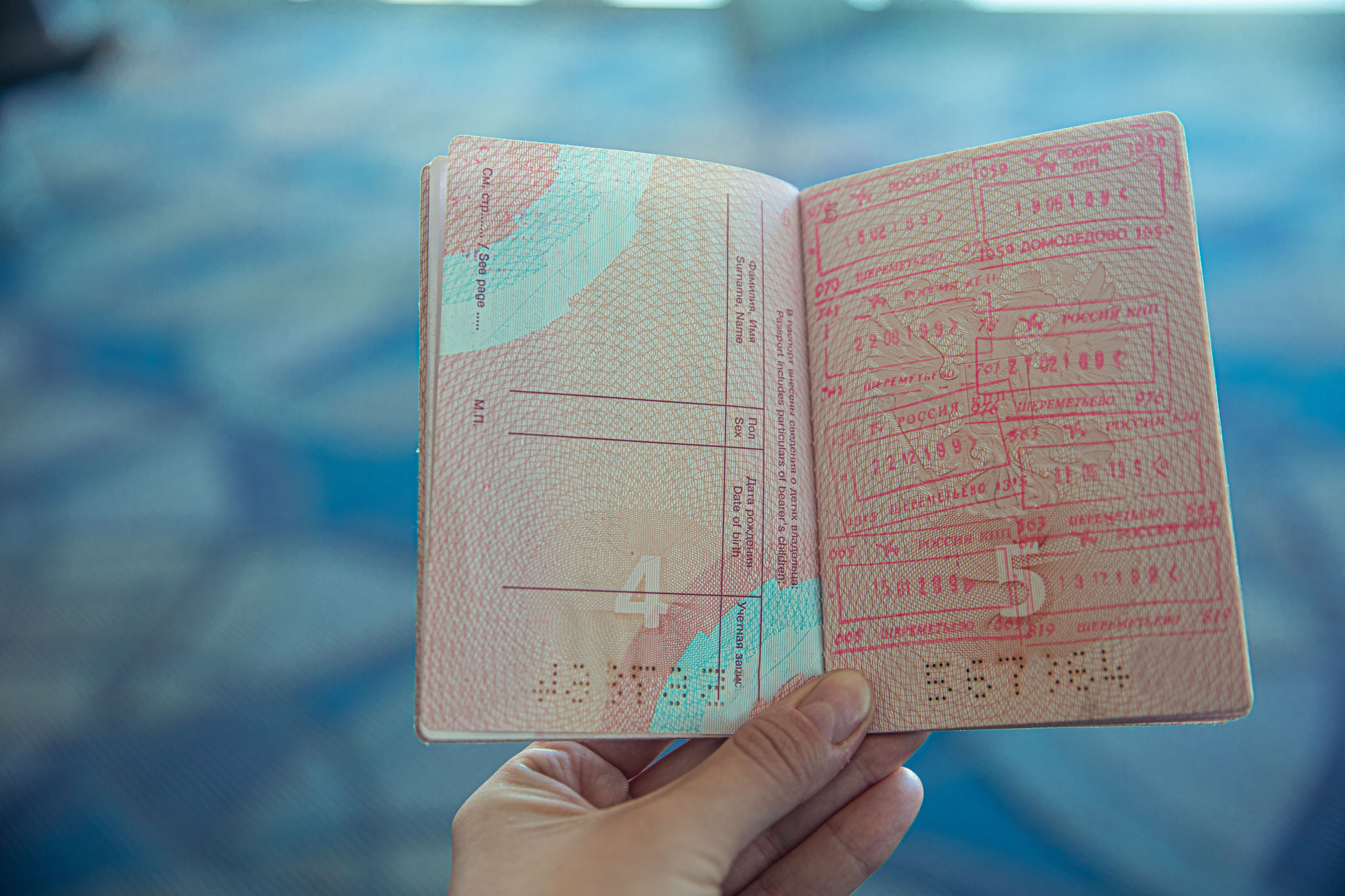 Close-up of an open passport displaying travel stamps in an airport setting